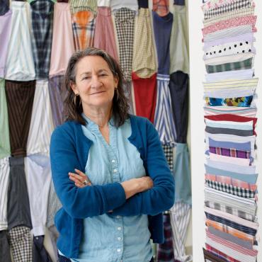 This is a photo of Rachel Breen in front of recent work titled "Piece work; sleeves and collars." The work in this photo is comprised of dis-assembled shirts and collars.