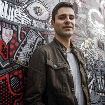 Photo of Ricardo Gallo standing in front of a mural