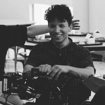 Tahiel Jimenez Medina, 20-something Latino masculine presenting person smiles with a camera on their hands.