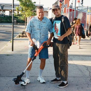 Taryn Ward, 25 years old, embracing a man with a weedwacker on Coney Island.