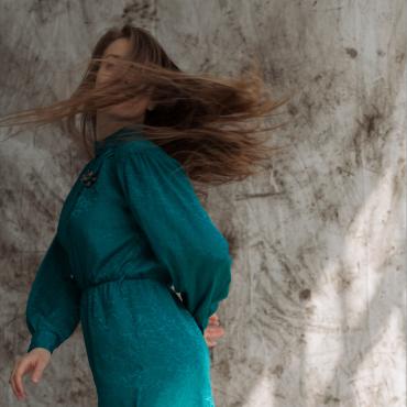 A woman with long hair and blue dress is captured while spinning in a circle.