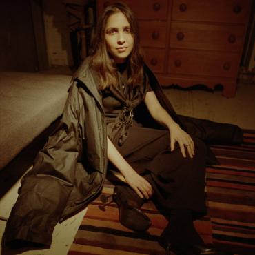 Selwa aka Bergsonist, a thirty Moroccan woman musician, sitting on the floor of a music studio for a photo shoot.