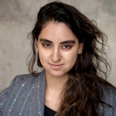 "Karina Dandashi, an Arab-American filmmaker wearing a blazer, posing for the camera."