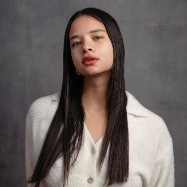 Liana Mack, a 30-something mixed-race writer in a white sweater, gazes at the camera.