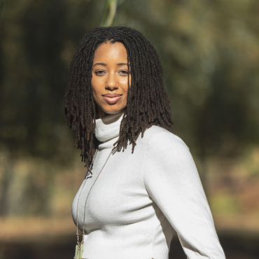 A. E. Wynter, a 30-something Black woman with brown eyes and medium-length dreadlocks facing the camera.