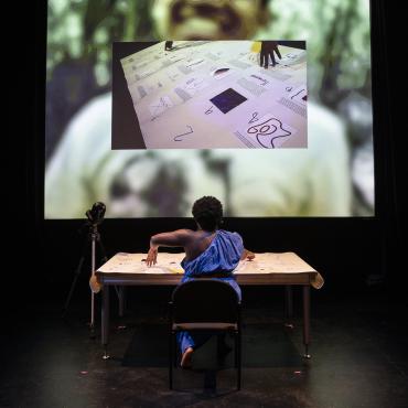 Ogemdi Ude facing a screen, sitting at a desk with her back to the camera.