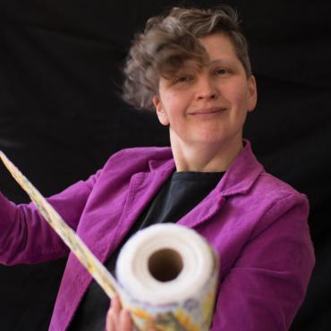 Anna Samo, an animation filmmaker playfully holding a roll of toilet paper painted by the artist as a part of her most recent animated short