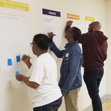 Image of three workshop participants writing ideas on posters.